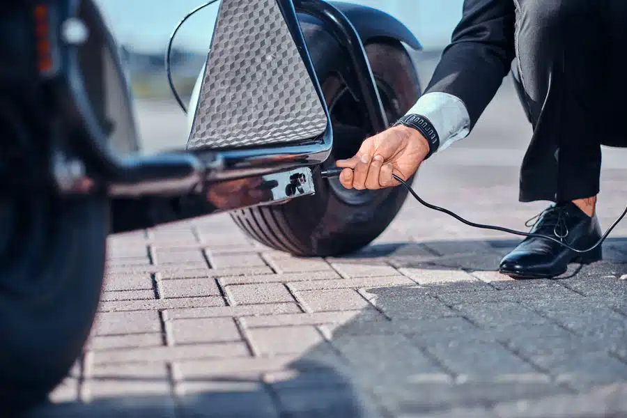 hombre-elegante-cargando-su-scooter-electrico-cargador-estacionamiento-especial